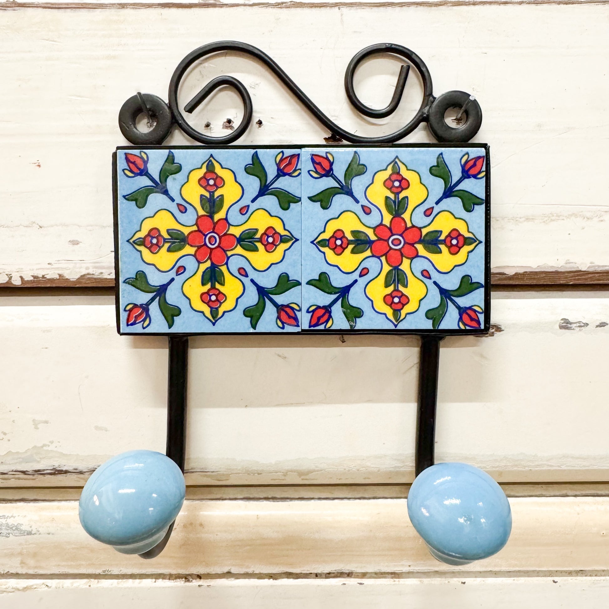 Decorative wall hook with colorful tile design and blue knobs 