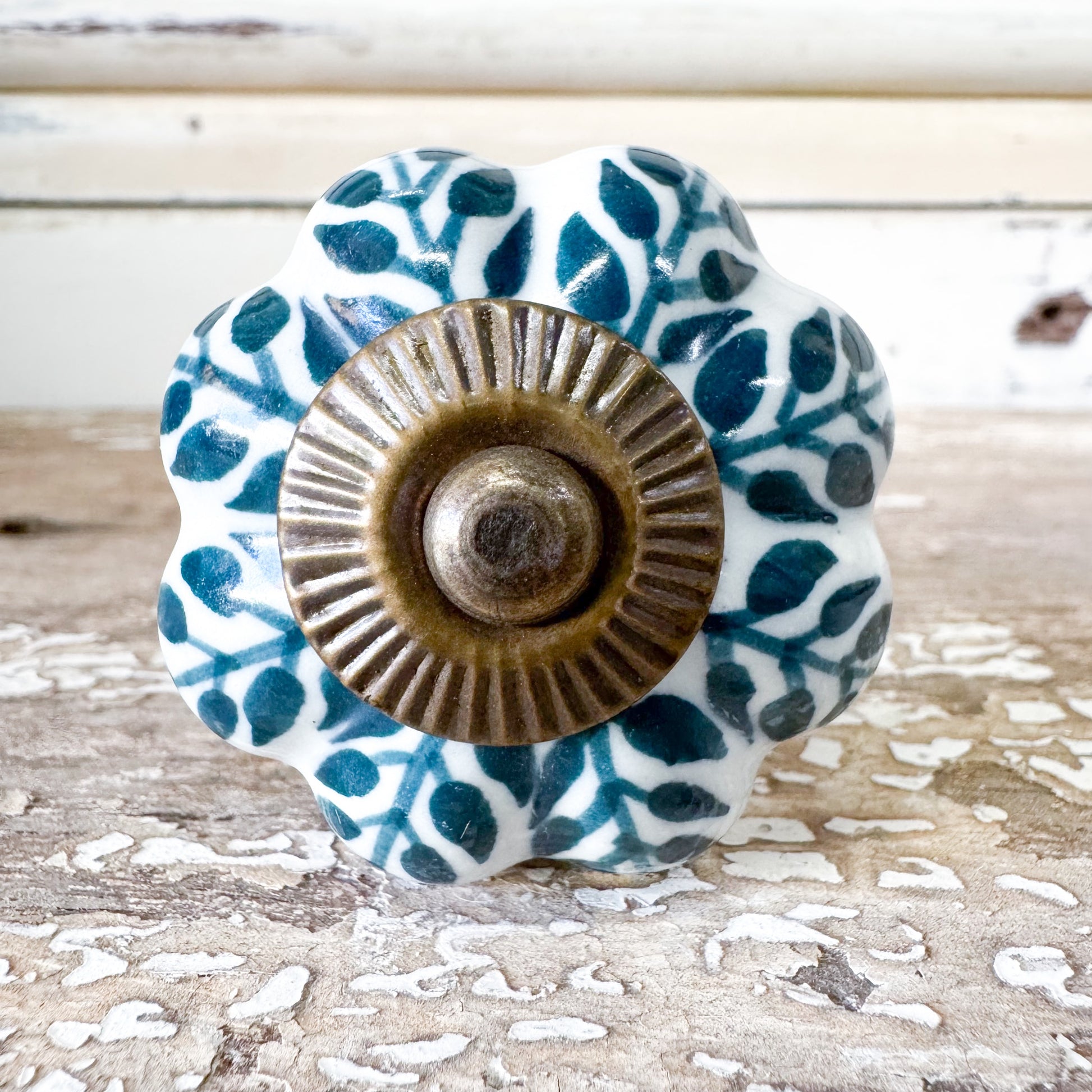 Decorative ceramic knob with TURQUOISE floral pattern on a wooden surface