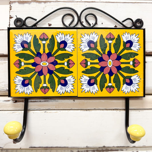 Decorative wall hook with floral tile designs on a yellow background